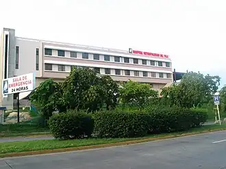 Hospital Metropolitano Dr. Pila al lado norte de la avenida Las Américas, mirando al noreste, en el barrio Canas Urbano