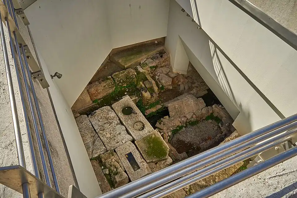 Eridanos entubado en sus dos canales (derecha de la imagen) arriba canal con cobertura de ladrillos en «v» abajo canal obstruido con grava Ubicado debajo de la plaza Monastiraki.