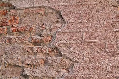 Ejemplo de protección de ladrillos foráneos cocidos mediante un revestimiento sobre el que se ha realizado un albañilería (falsas juntas).