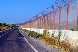 Valla metálica roja sobre un muro blanco
