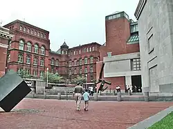 Entrada de Raoul Wallenberg Place del USHMM. Tres grandes fachadas de ladrillo y piedra caliza. En primer plano, una estatua moderna de arte negro.