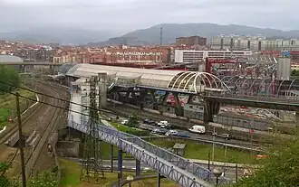 Vista de un viaducto con vías de metro, encima de las vías del BPT, en tierra, y que se vé como se bifurcan, viniendo hacia el punto de vista la vía doble y alejándose a la derecha la vía única y la del metro.