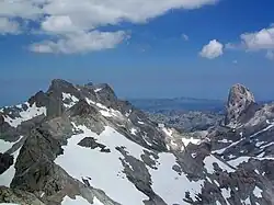 Vista desde la cumbre hacia el norte: Torre Cerredo, a la izquierda; el Naranjo de Bulnes, a la derecha; y la sierra de Cuera al fondo.