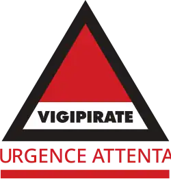 Triángulo Vigipirate con "Urgence Attentat" en letras rojas