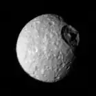 Mimas a una distancia de 425.000 km; el cráter Herschel se encuentra arriba a la derecha.