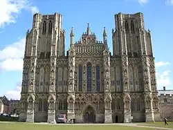 La catedral de Wells tiene torres, una galería esculpida y una ventana de lanceta. La fachada de Wells, a diferencia de la de Exeter, presenta una composición unificada y equilibrada. Sin embargo, las torres aparecen truncadas porque se pretendía que tuvieran agujas, que no fueron construidas