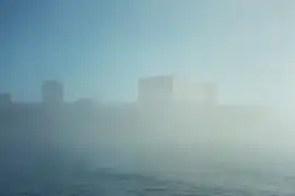 El palacio del Pharo semioculto por la niebla estival.